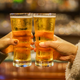 two hands doing cheers with beer